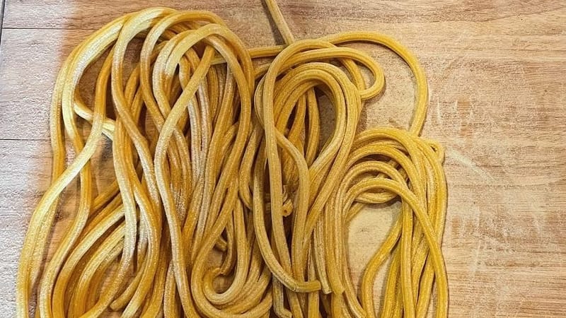 Fresh bucatini Anthony made by hand, dusted with semolina on a wood board