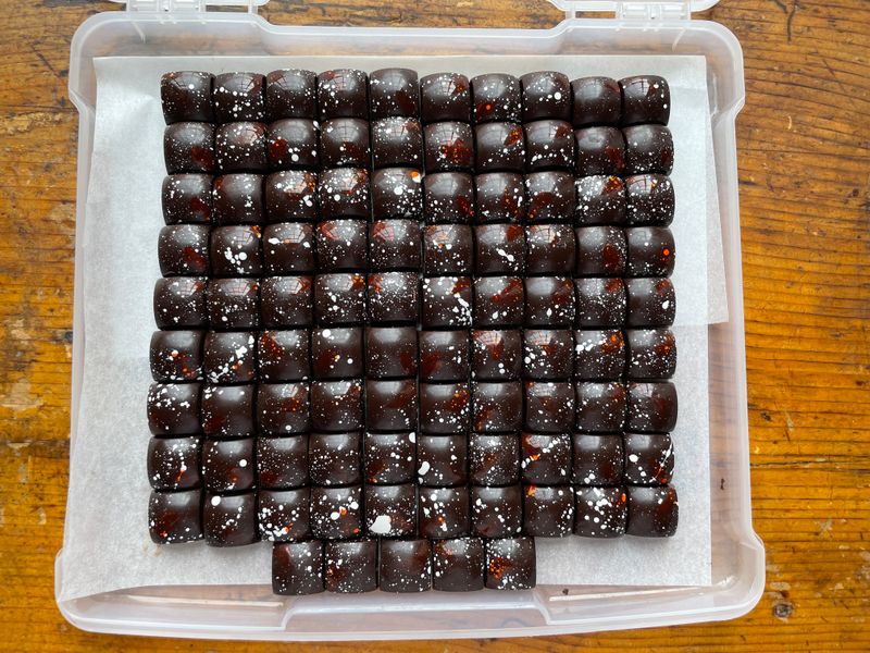 A tray of dark plum bonbons set in a grid