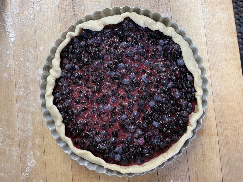 A whole blueberry pie in a fluted tart pan