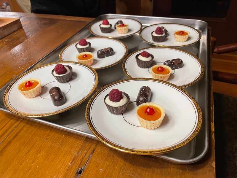 White plates of plated chocolates with citrus and berry garnish