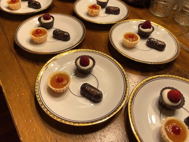 White plates of plated chocolates with a berry garnish