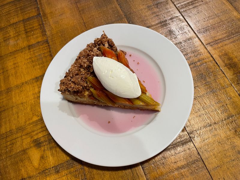 A slice of rhubarb tart with a quenelle of cream in pink sauce