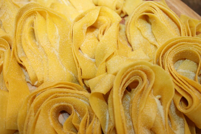 Close-up of hand-rolled pappardelle nests dusted with semolina