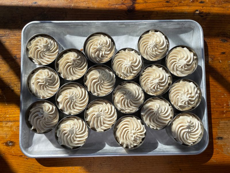 A tray of pecan cream tarts finished with piped cream swirls