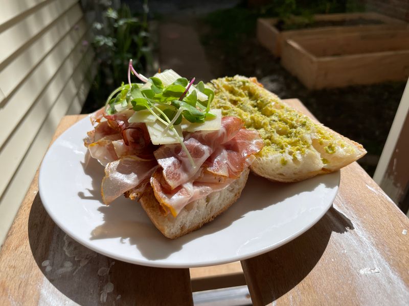 Prosciutto sandwich with greens and garlic bread on a plate